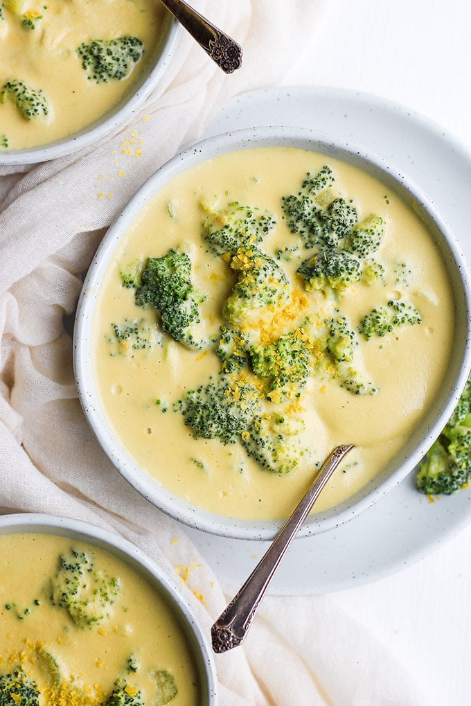 A bowl of dairy free creamy broccoli cheese whole30 soup garnished with whole broccoli florets. 
