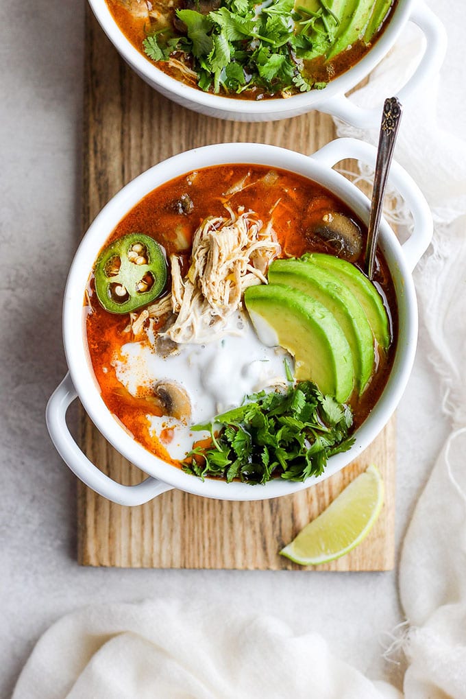 A bowl of creamy white chicken chili whole30 soup garnished with avocado and jalapeno cooked in the slow cooker.