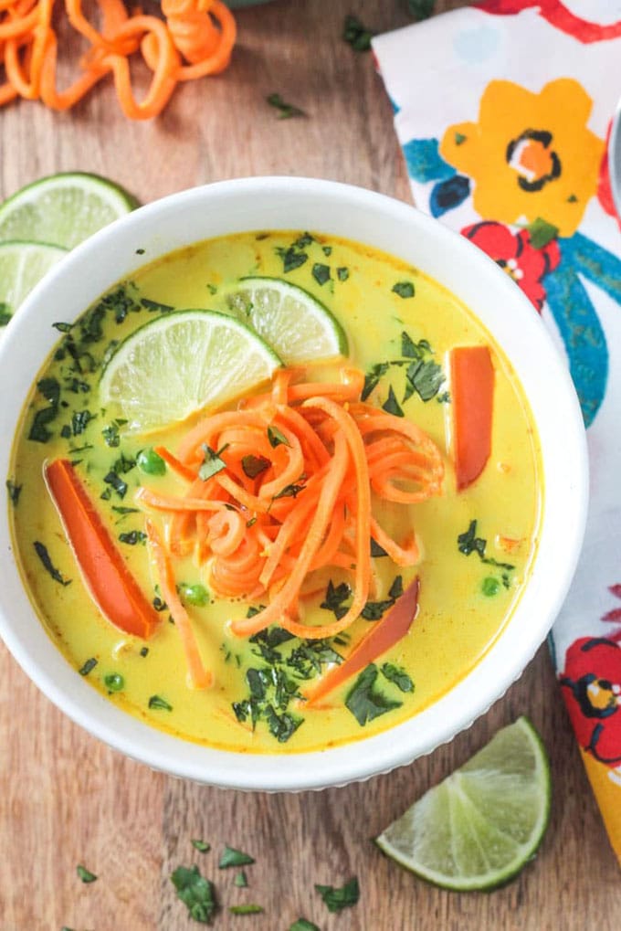 Coconut curry whole30 soup with sweet potato noodles in a white bowl on a wood background.