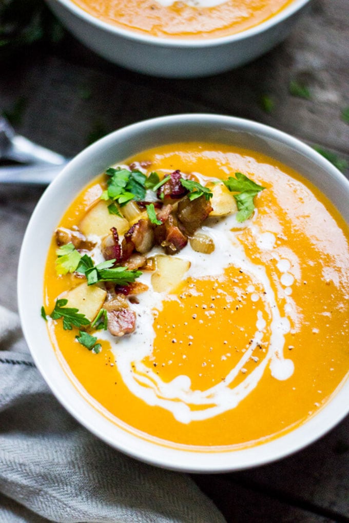 Creamy butternut squash whole30 soup garnished with bacon and apple. 