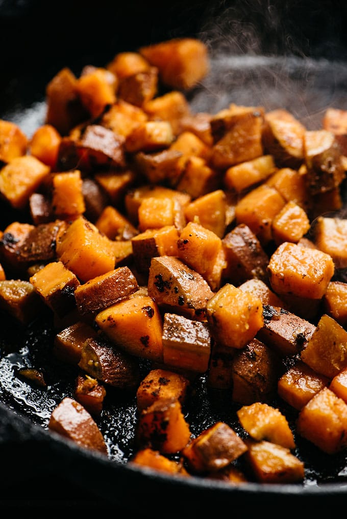 Seared cubes of sweet potatoes in a cast iron skillet.
