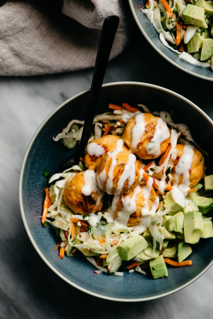 Buffalo chicken meatballs over no mayo coleslaw with diced avocado and ranch dressing.