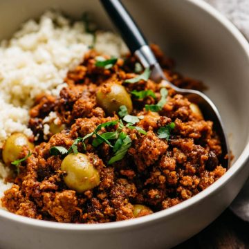 A low carb and Whole30 picadillo recipe served over cauliflower rice in a tan bowl.