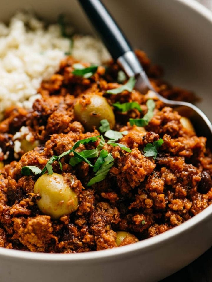 A low carb and Whole30 picadillo recipe served over cauliflower rice in a tan bowl.
