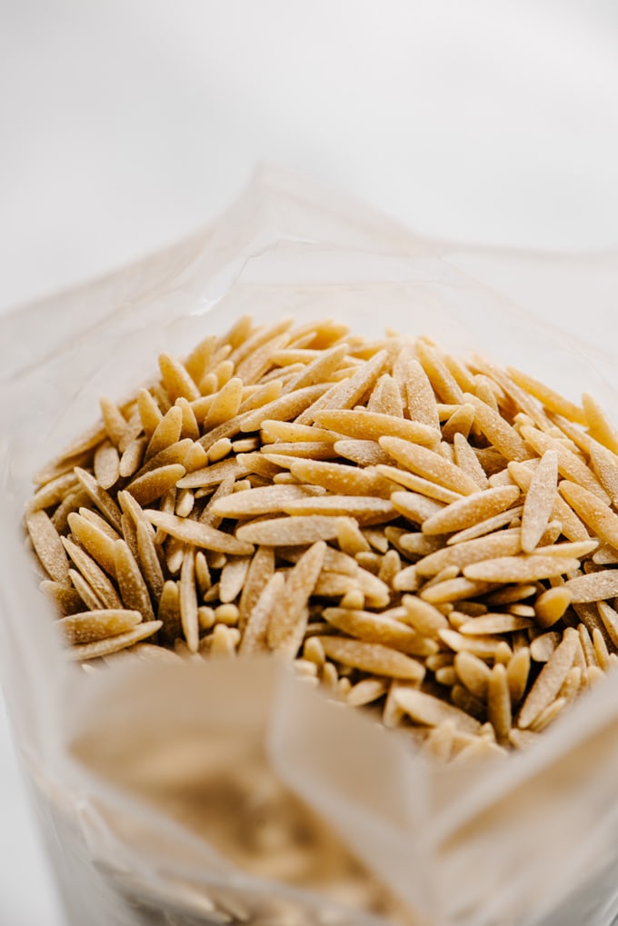 A close-up image of whole wheat orzo pasta in a bag.