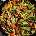 Steak stir fry with vegetables in a cast iron skillet.