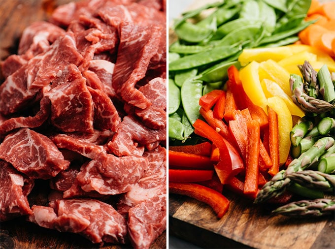 Thinly sliced beef and raw stir fry vegetables on cutting boards.