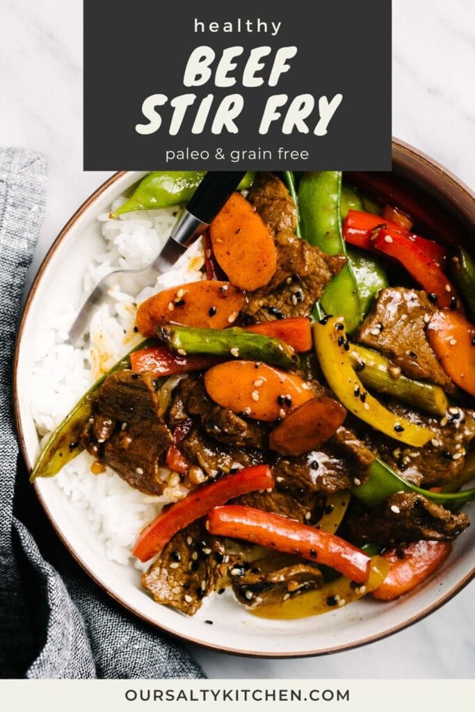 Steak stir fry with rainbow vegetables over steamed white rice in a low bowl, garnished with sesame seeds; title bar at the top reads "healthy beef stir fry; grain free and paleo".