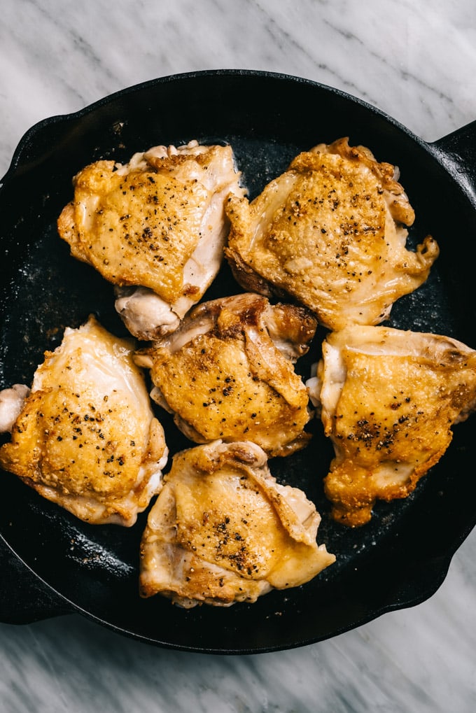 Browned chicken thighs in a cast iron skillet.