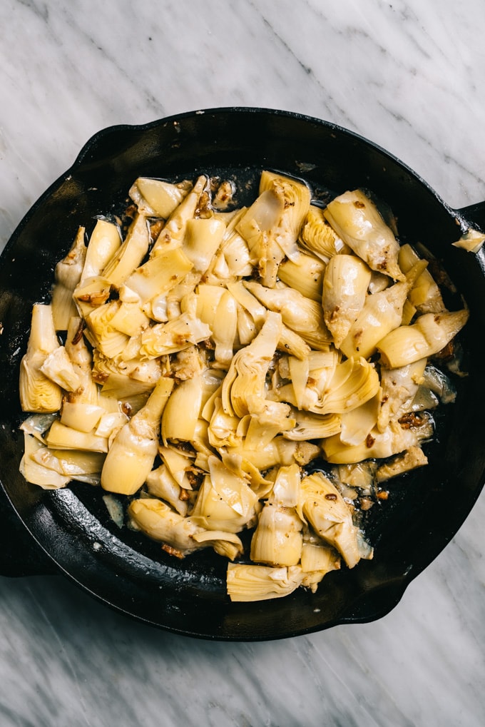 Artichoke hearts tossed with garlic in a skillet.
