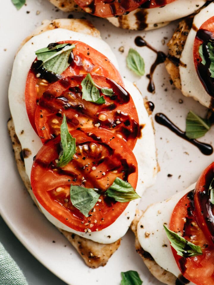 A platter of grilled italian caprese chicken drizzled with aged balsamic vinegar.