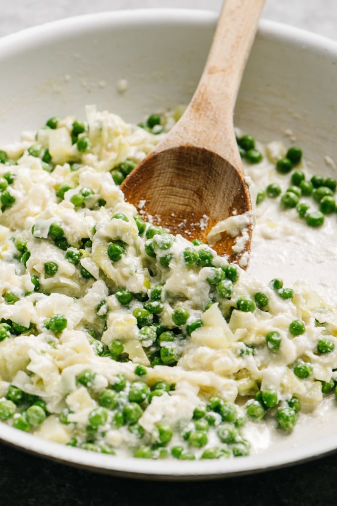 Ricotta sauce with peas in a skillet.