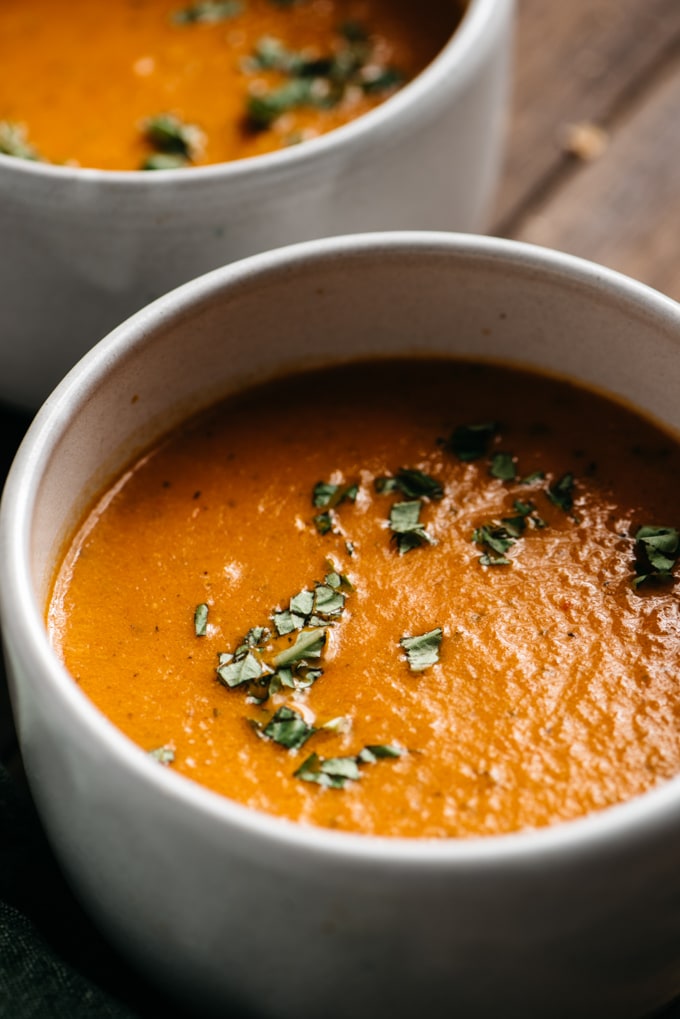 A bowl of homemade roasted tomato soup garnished with chopped basil.