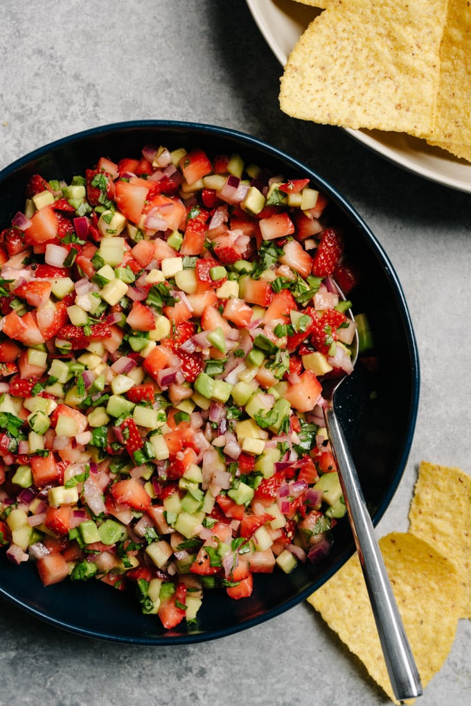 A bowl of vegan strawberry avocado salsa with basil, cucumber, and macerated red onions.