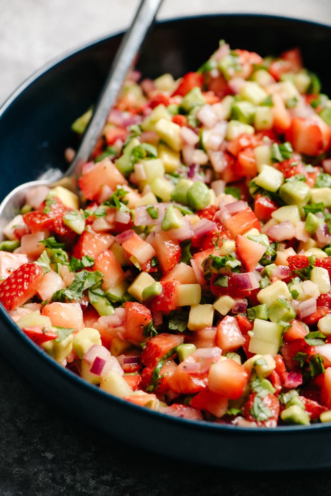 A close up image of sweet strawberry avocado salsa with cucumber and basil.