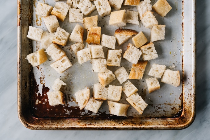 From above, cubes of sourdough on a baking sheet tossed with olive oil and salt for making croutons.