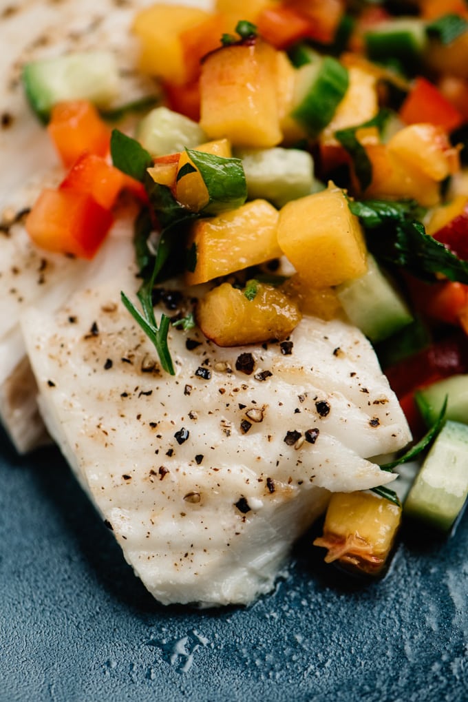 Side view, oven baked halibut fillet topped with fresh peach salsa.