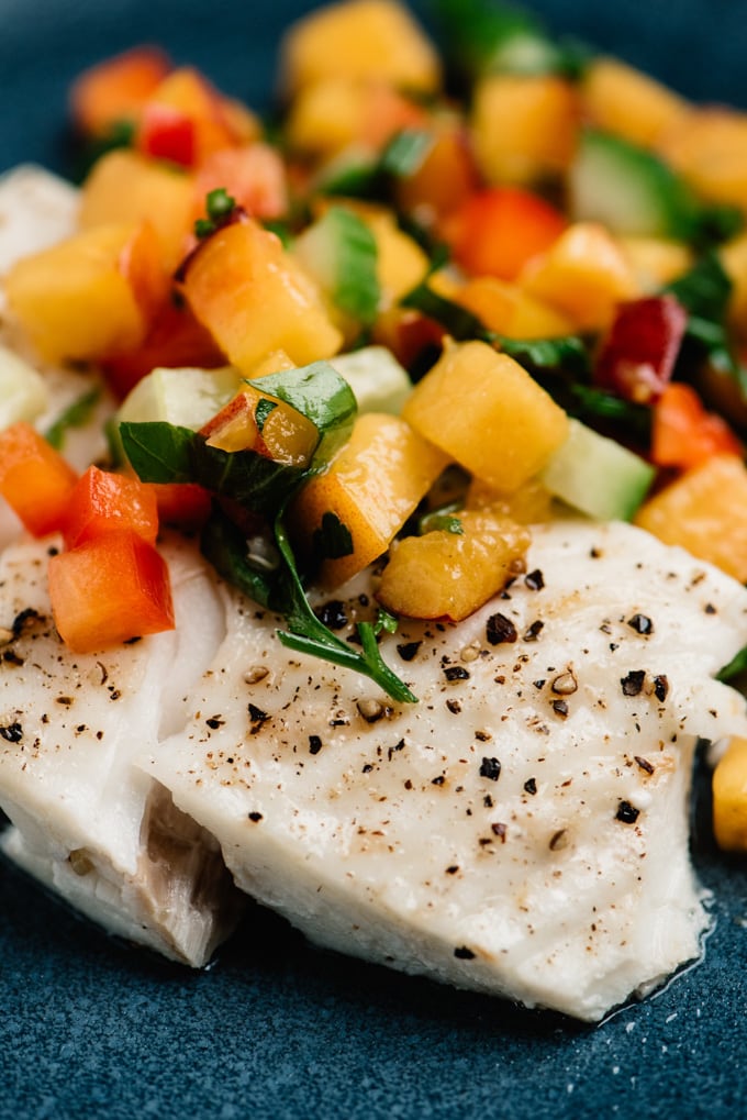 Side view, baked halibut fillet topped with fresh peach salsa.