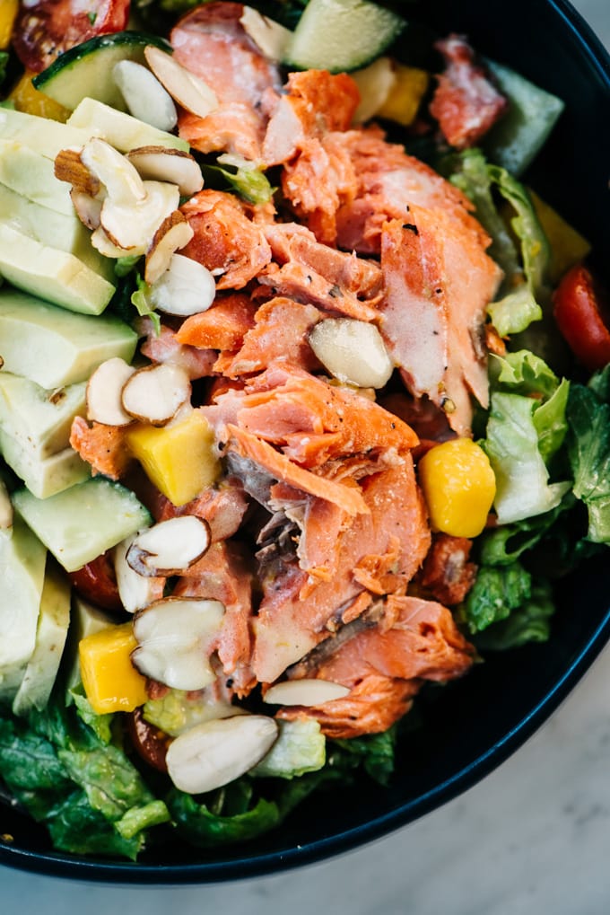 From above, a detail view of salmon and avocado over salad greens with creamy lemon dressing.