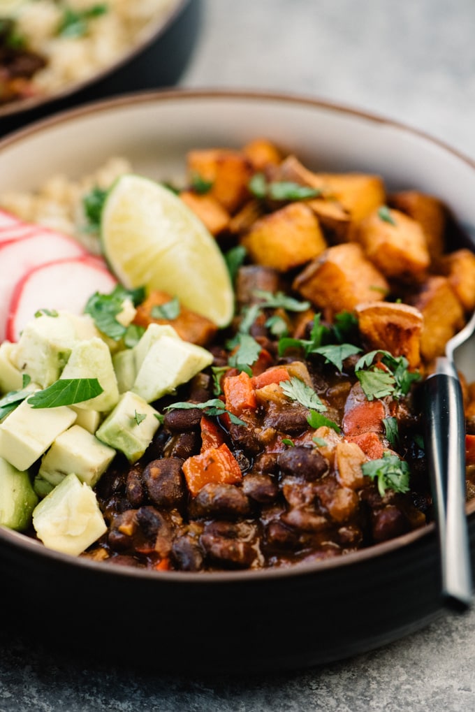 Side view, vegan black bean buddha bowl with quinoa, avocado, and roasted sweet potatoes. 