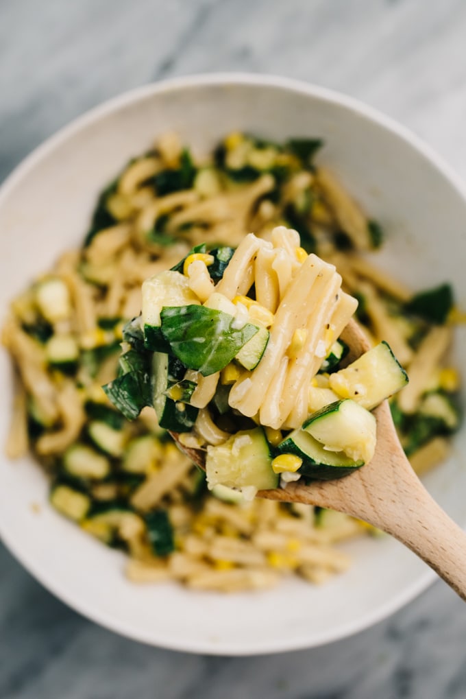 Close up spoonful of summer pasta with zucchini and sweet corn.