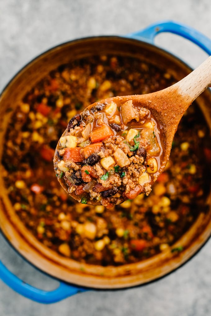 A spoonful of taco soup held above a dutch oven filled with taco soup.
