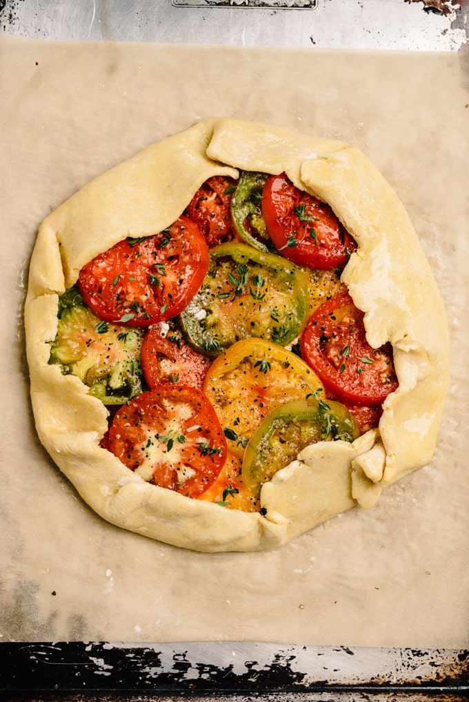 A prepared tomato galette on a baking sheet before being transferred to the oven.