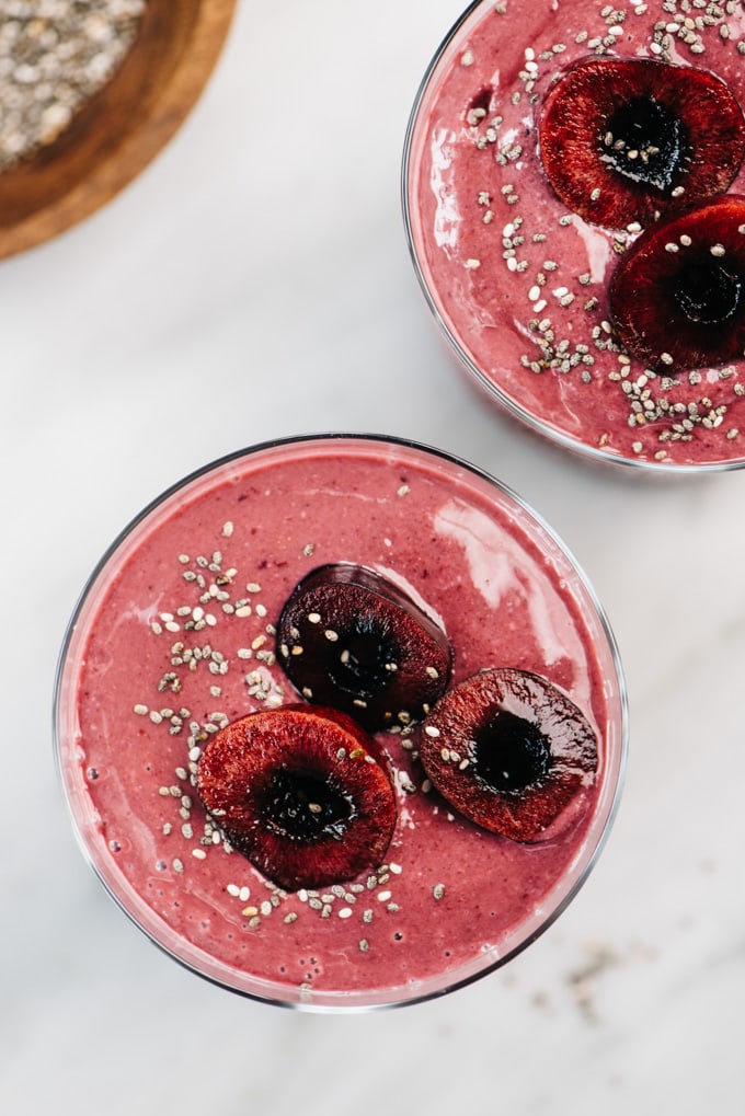 From above, two vegan cherrie smoothies on a marble table with a small bowl of chia seeds on the side.