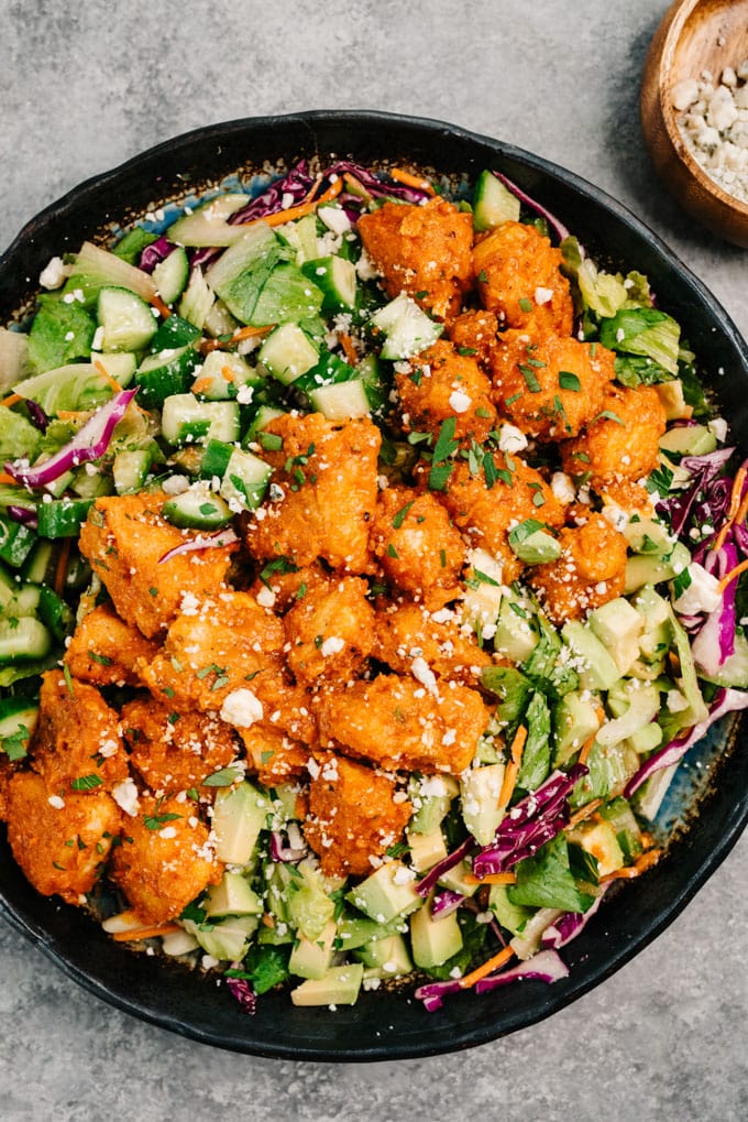 Buffalo chicken salad with romaine, cabbage, celery, carrots, cucumber, avocado, and blue cheese crumbles on a large salad platter.