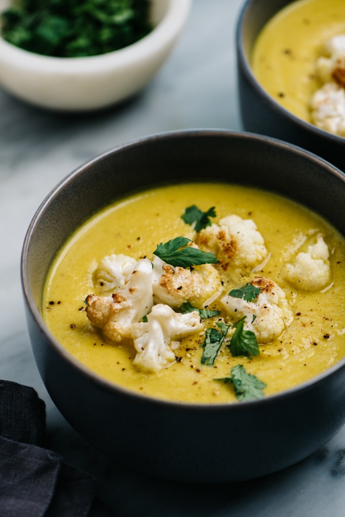 A bowl of curried cauliflower soup topped with roasted cauliflower and cilantro.