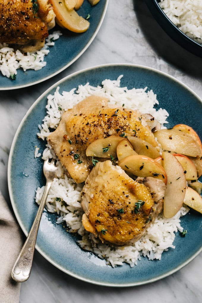 Apple cider chicken with baked apples over rice on a blue plate.