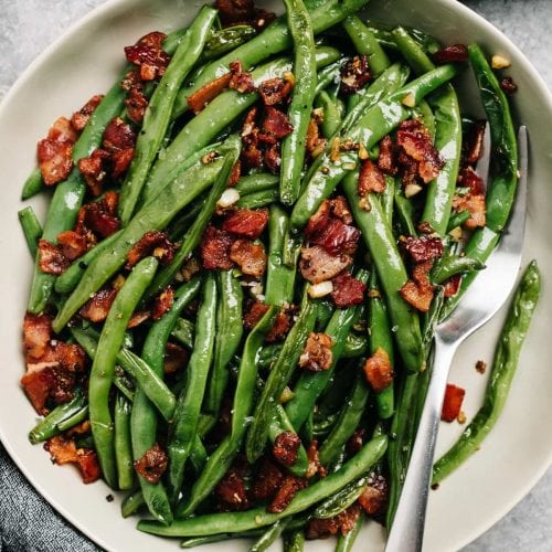 From above, green beans with bacon and garlic in a serving bowl.