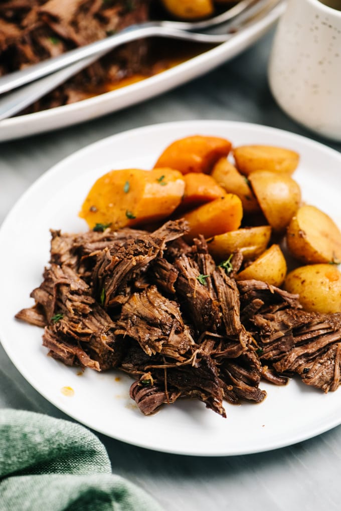 A plate of shredded italian pot roast cooked in the instant pot with potatoes and carrots.