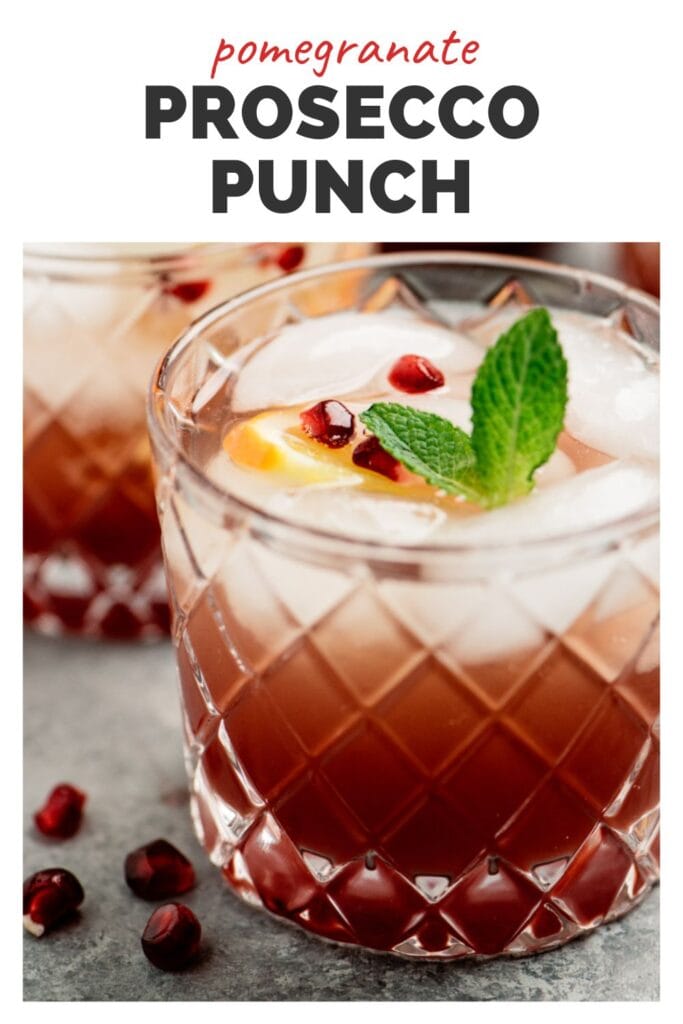 Side view, two prosecco punch cocktails with pomegranate on a concrete background, garnished with pomegranate seeds, orange slices, and a mint sprig; title bar at the top reads "pomegranate prosecco punch".