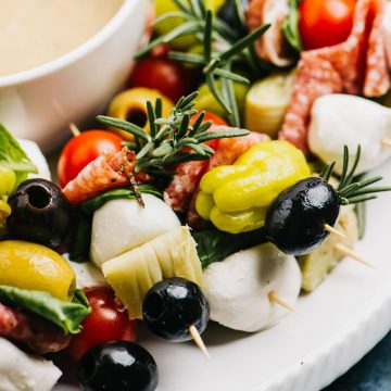 Side view, antipasto skewers on a platter served with anchovy vinaigrette.