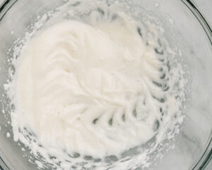 An egg white beat to soft peaks in a mixing bowl.