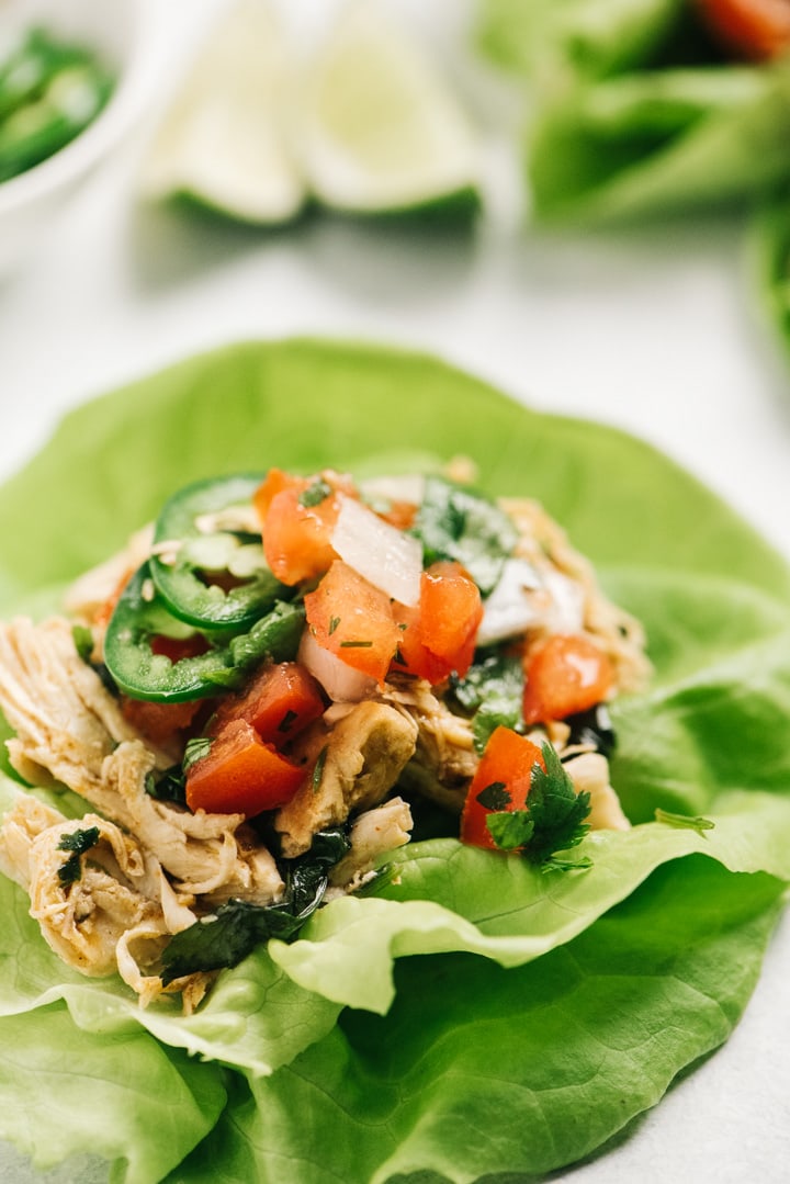 Instant pot cilantro lime chicken stuffed into a lettuce taco and topped with pico de gallo and jalapenos.