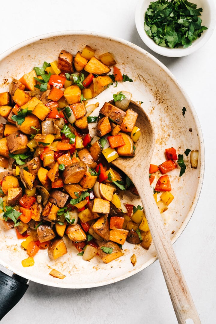 From overhead, sweet potato hash with peppers in a pan.