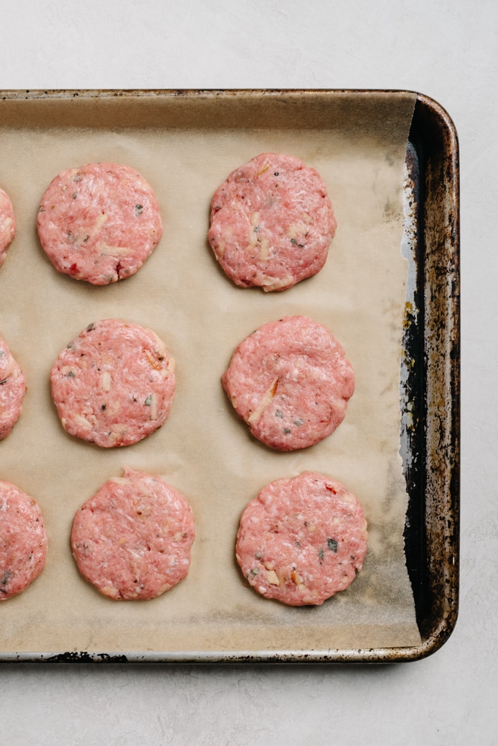 Whole30 breakfast sausage patties on a parchment lined baking sheet.