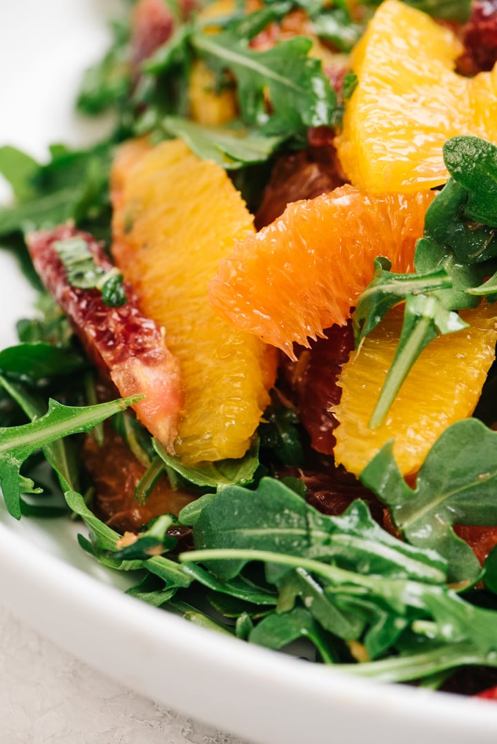 Side view, citrus salad with a variety of oranges tossed with arugula, fresh mint, and a sweet citrus dressing.