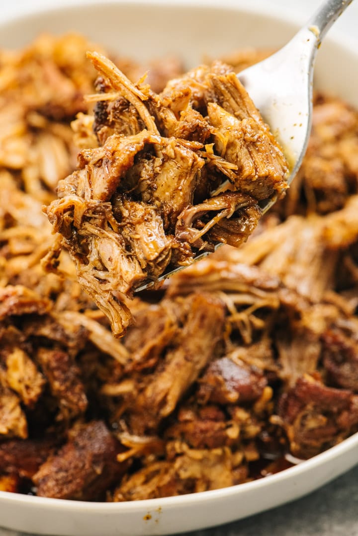 A bowl of pulled pork cooked in the instant pot with a silver serving fork.