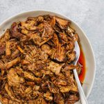 Instant pot pulled pork in serving bowl with a silver spoon.