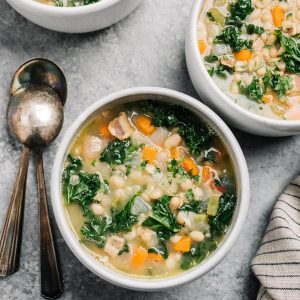 White bean and kale soup served in a white bowl