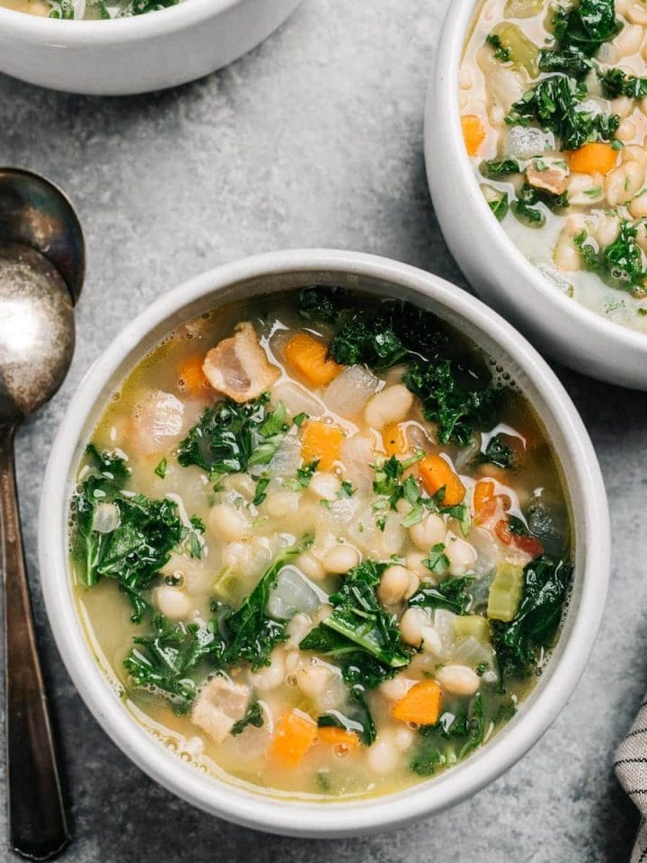 White bean and kale soup served in a white bowl