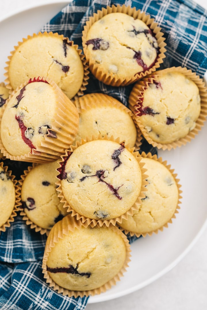 Blueberry cornbread muffins in a large white bowl lined with a blue kitchen towel.