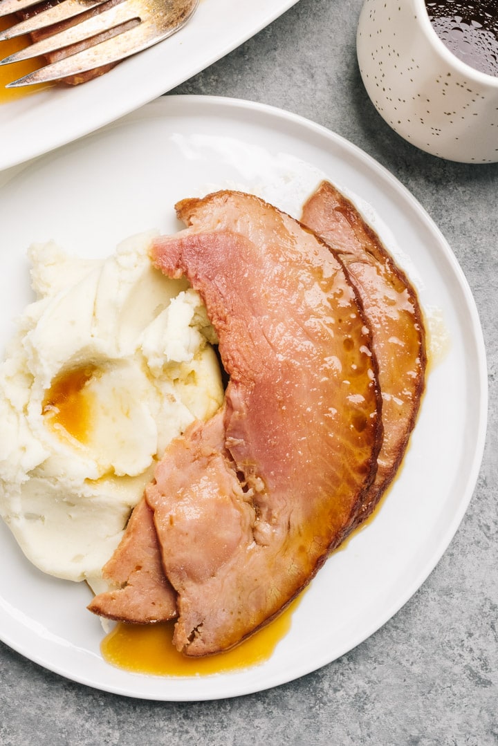 Spiral ham slices cooked in the Instant Pot served over mashed potatoes drizzled with maple orange glaze.