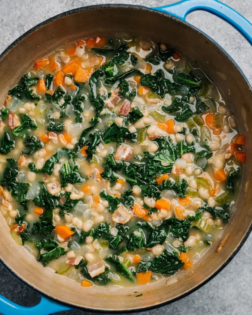 White bean and kale soup in a blue pot.