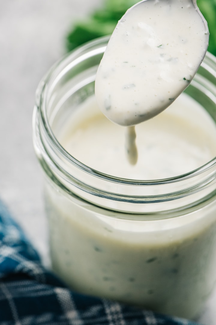 Whole30 ranch dressing dripping off the end of a spoon.