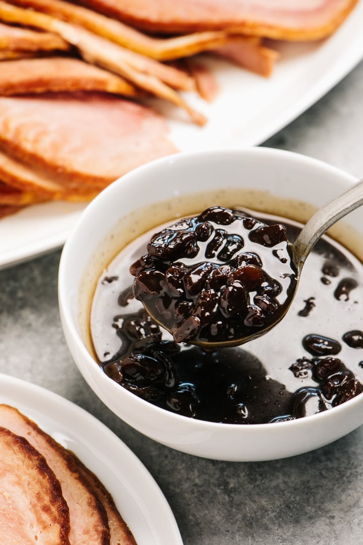 A ladle of raisin sauce hovering over a bowl.