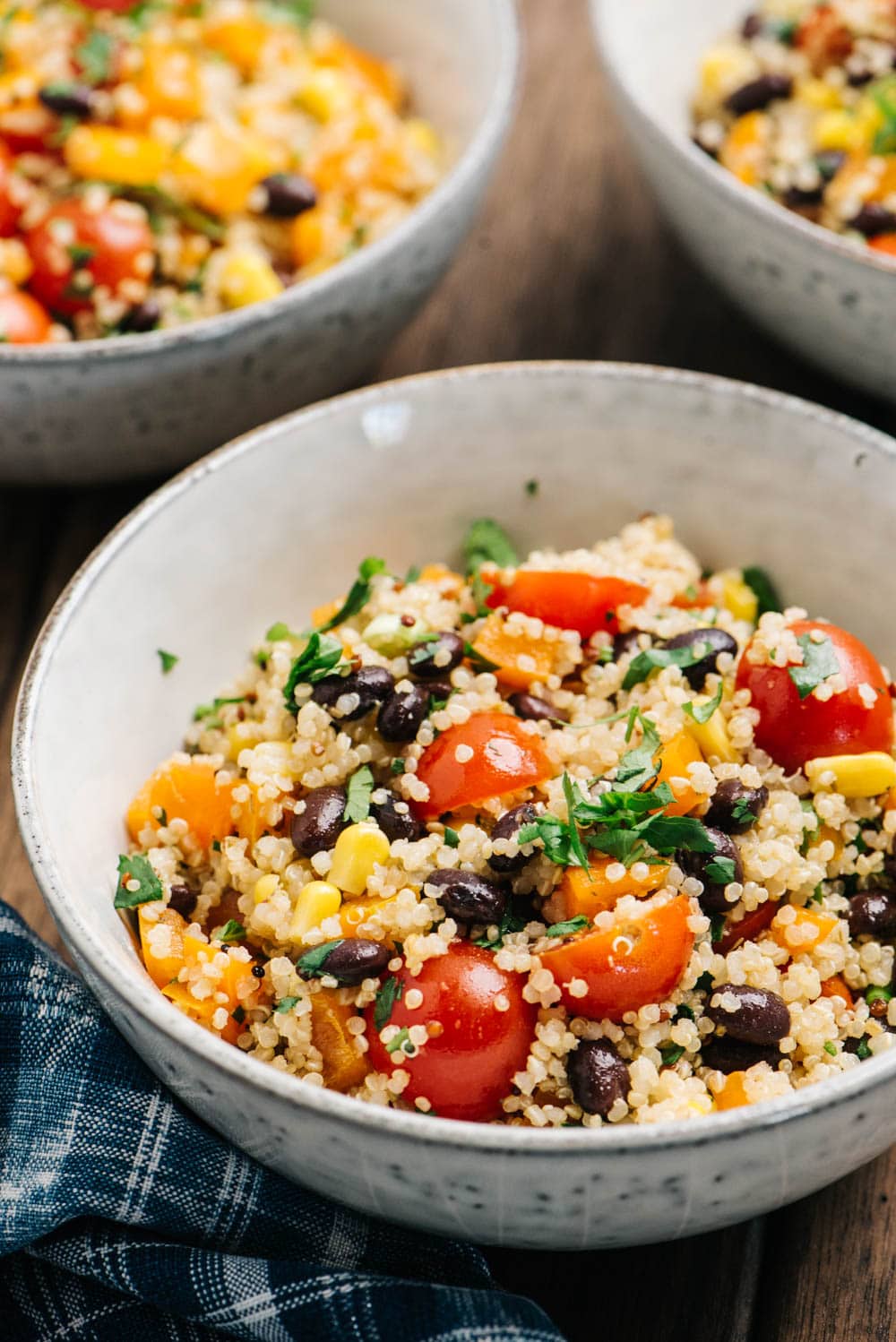 Three bowls of vegan quinoa salad with black beans and southwestern seasonings.